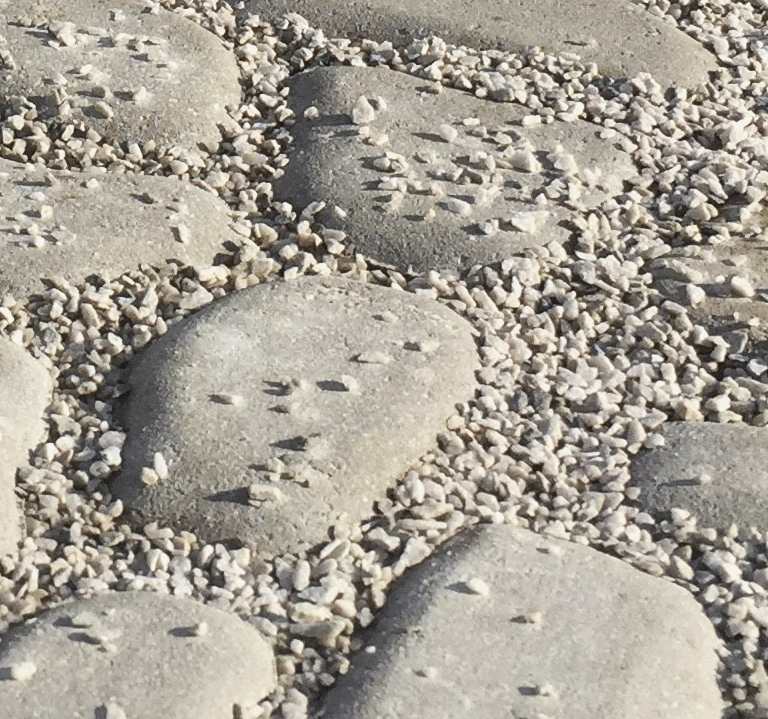 Närbild på rundade stenar med fin makadam emellan